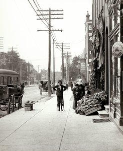 Un garçon avec des échasses devant le marché F.J. Voepel au 4874 Easton Avenue, au coin sud-est d